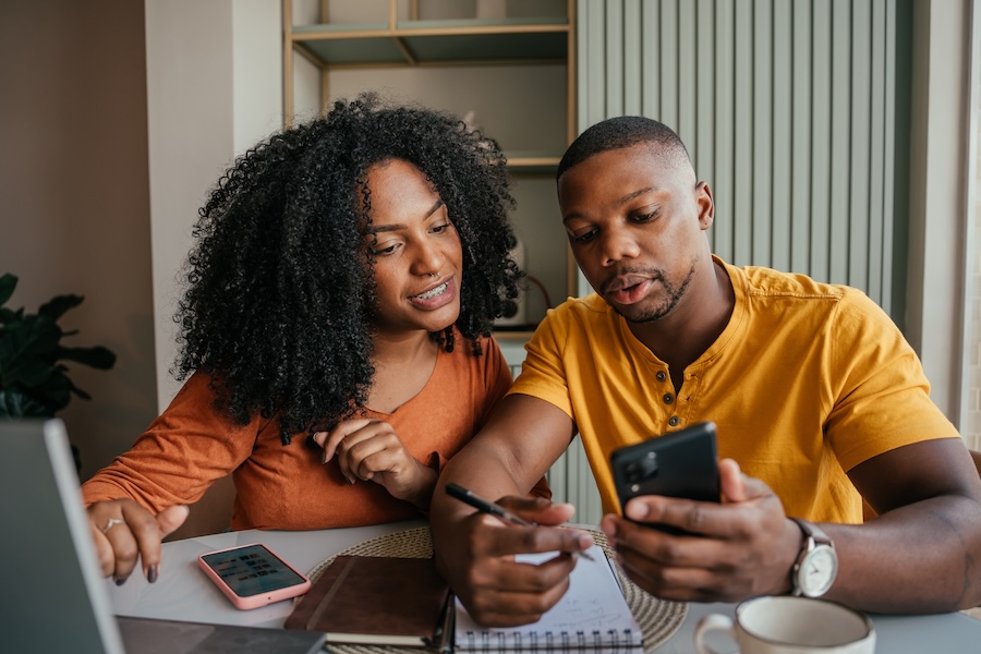 A couple sitting at a table reviewing their budget together on a phone