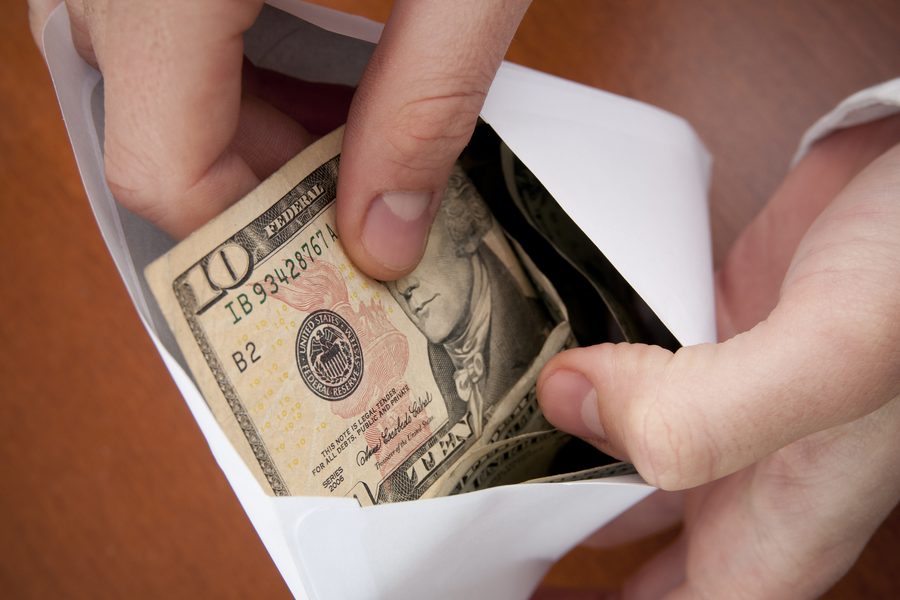 Hands pulling ten-dollar bills out of a cash envelope