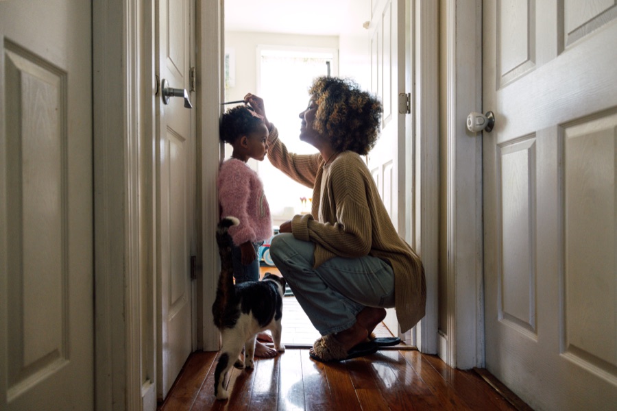 A parent measuring how tall their child has grown against a wall