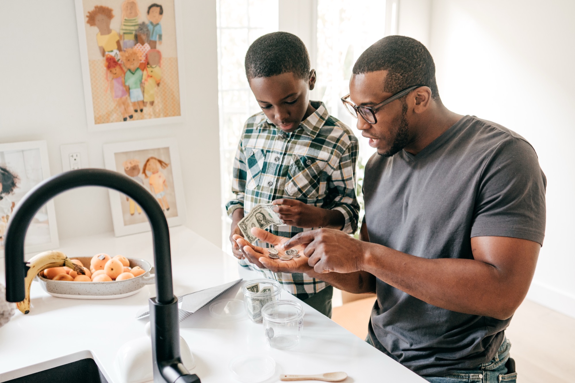 A father and son counting money together at a kitchen counter