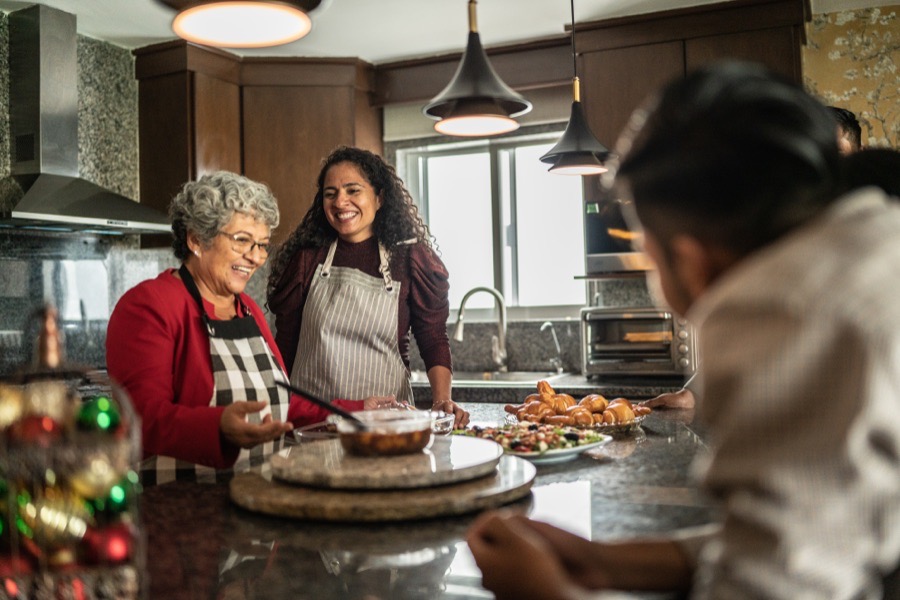 A family laughing together in the kitchen while preparing a holiday meal