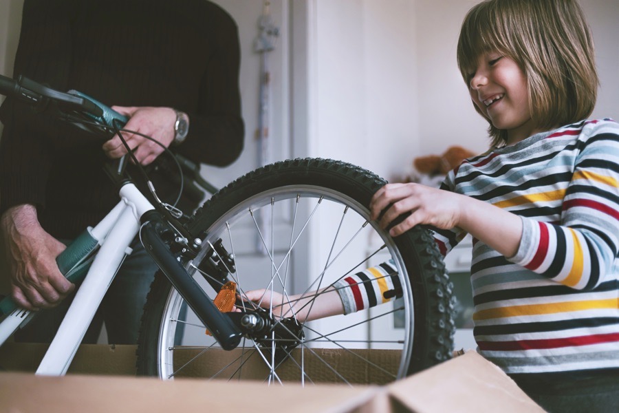 A delighted child unboxing a new bike with a parent