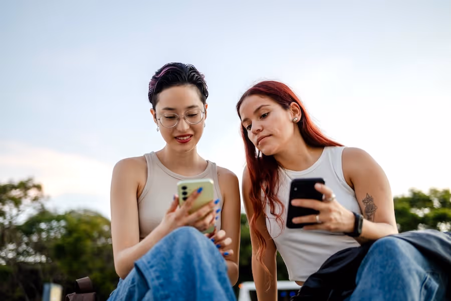 Two friends laughing while looking at their phones