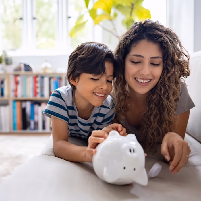 A parent and child putting money into a piggy bank