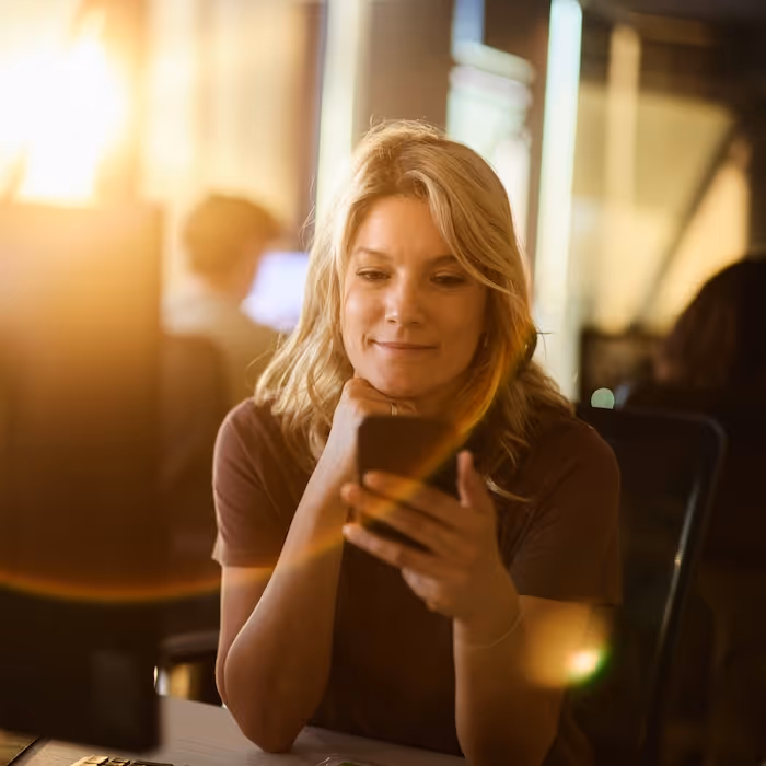 A smiling woman using the Crew app on her phone
